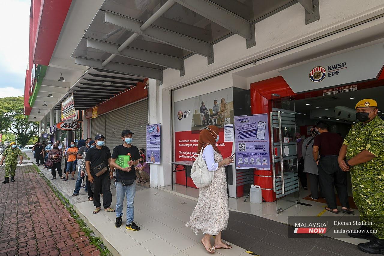 Rela members stand by as contributors queue to withdraw their savings under the i-Sinar scheme at the Bandar Baru Nilai Employees Provident Fund branch in Negeri Sembilan in this December 2020 file picture.