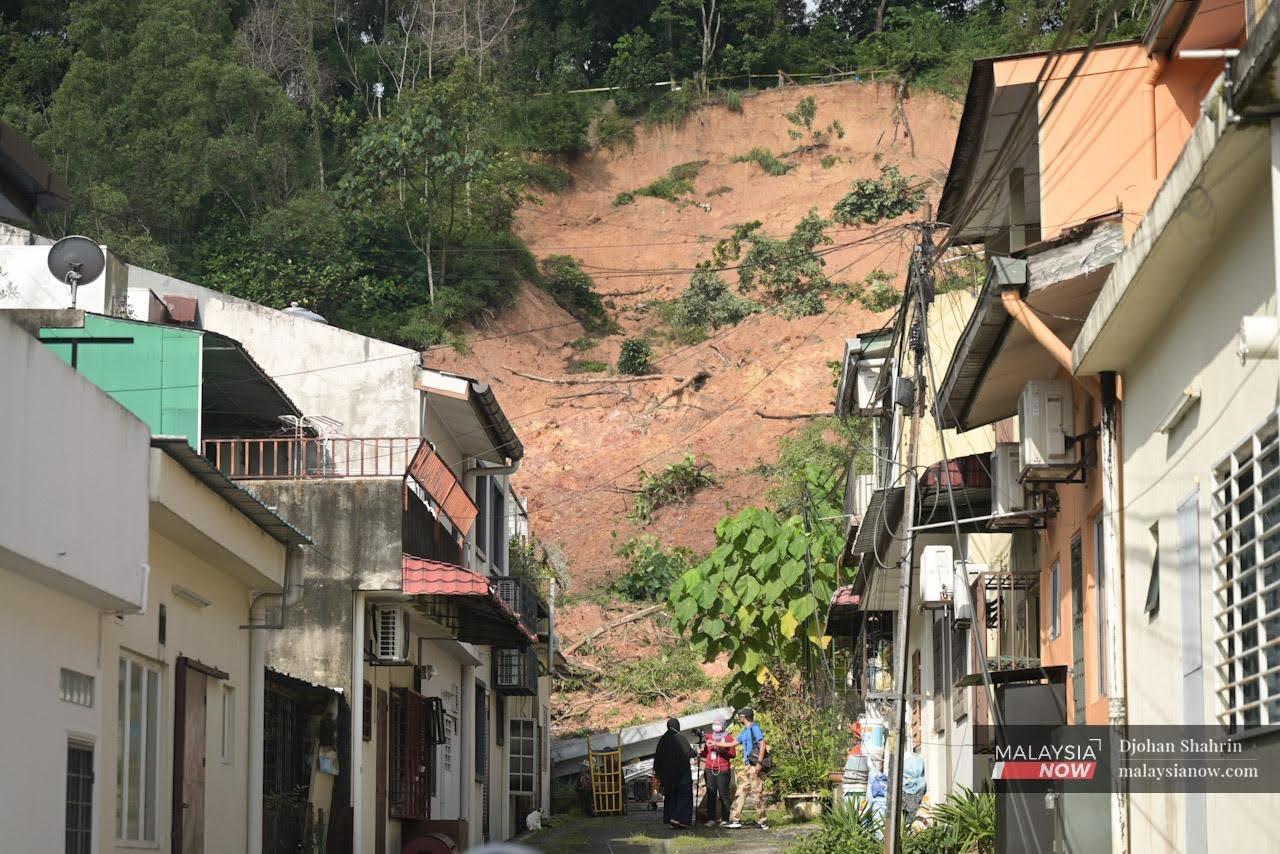 Residents seen at the site of a landslide in the Taman Bukit Permai 2 housing area in Ampang.