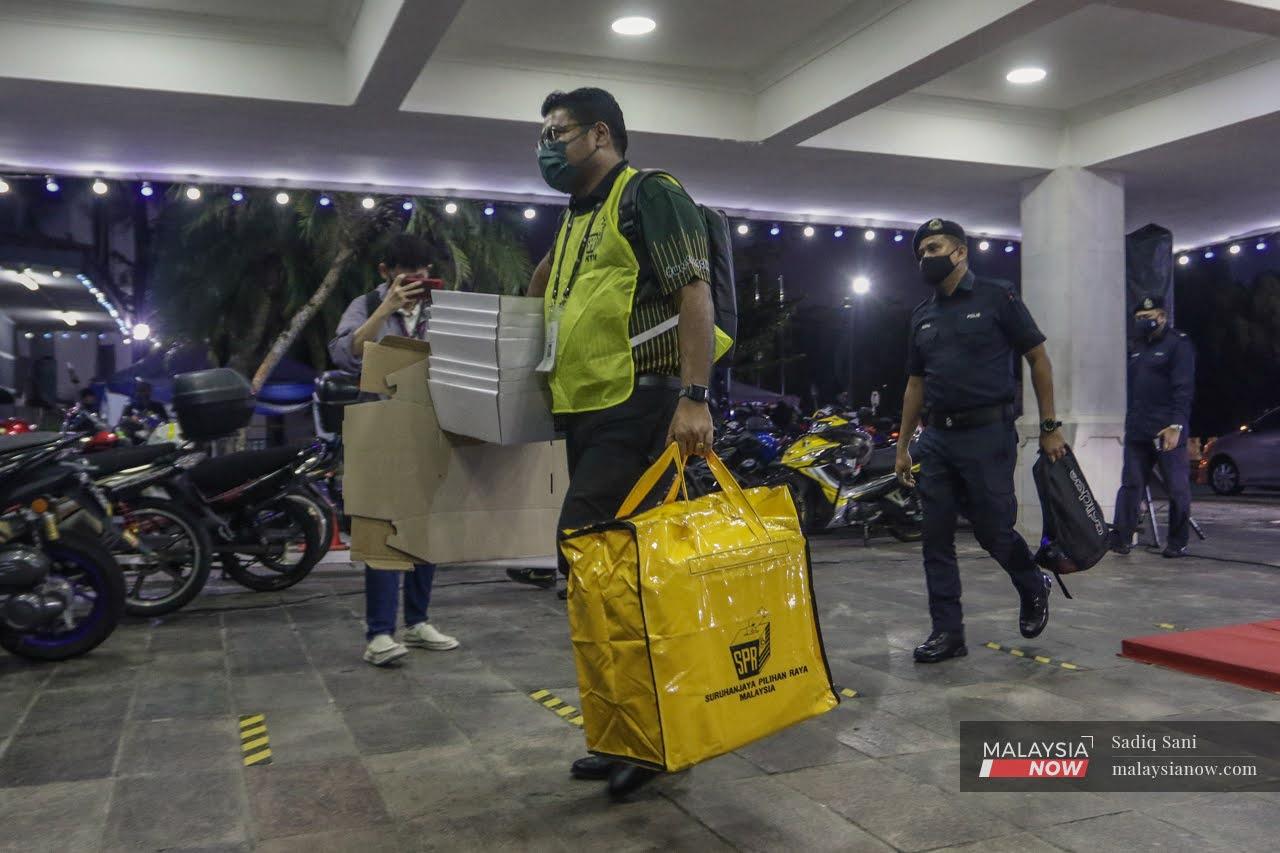 An officer from the Election Commission carries a yellow bag of ballot papers to the official vote counting centre in Perling during the Johor election on March 12.
