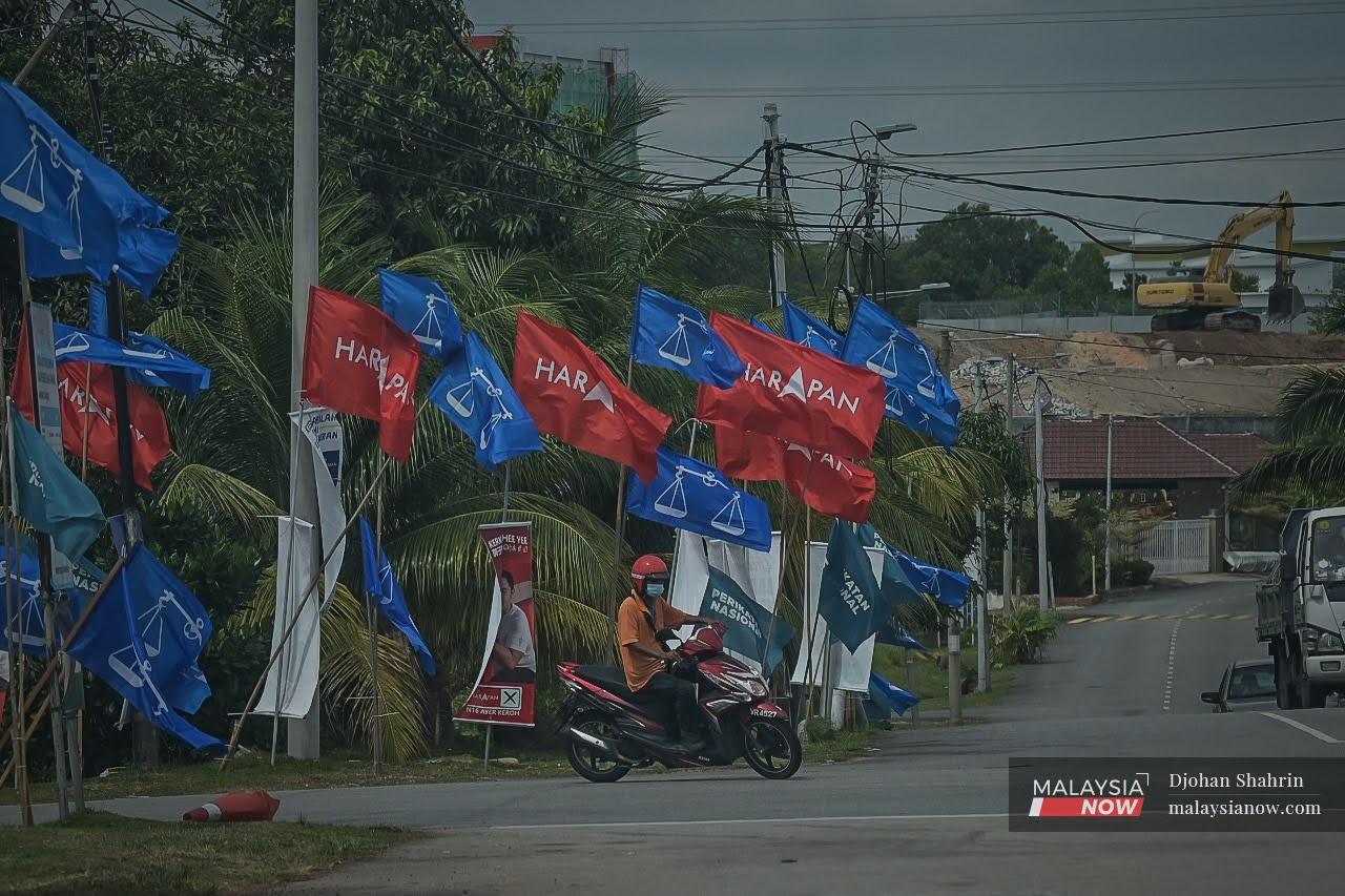A motorcyclist pauses at a junction decked out in the flags of Pakatan Harapan, Perikatan Nasional and Barisan Nasional in Bukit Beruang, Melaka, ahead of the state election there last November.