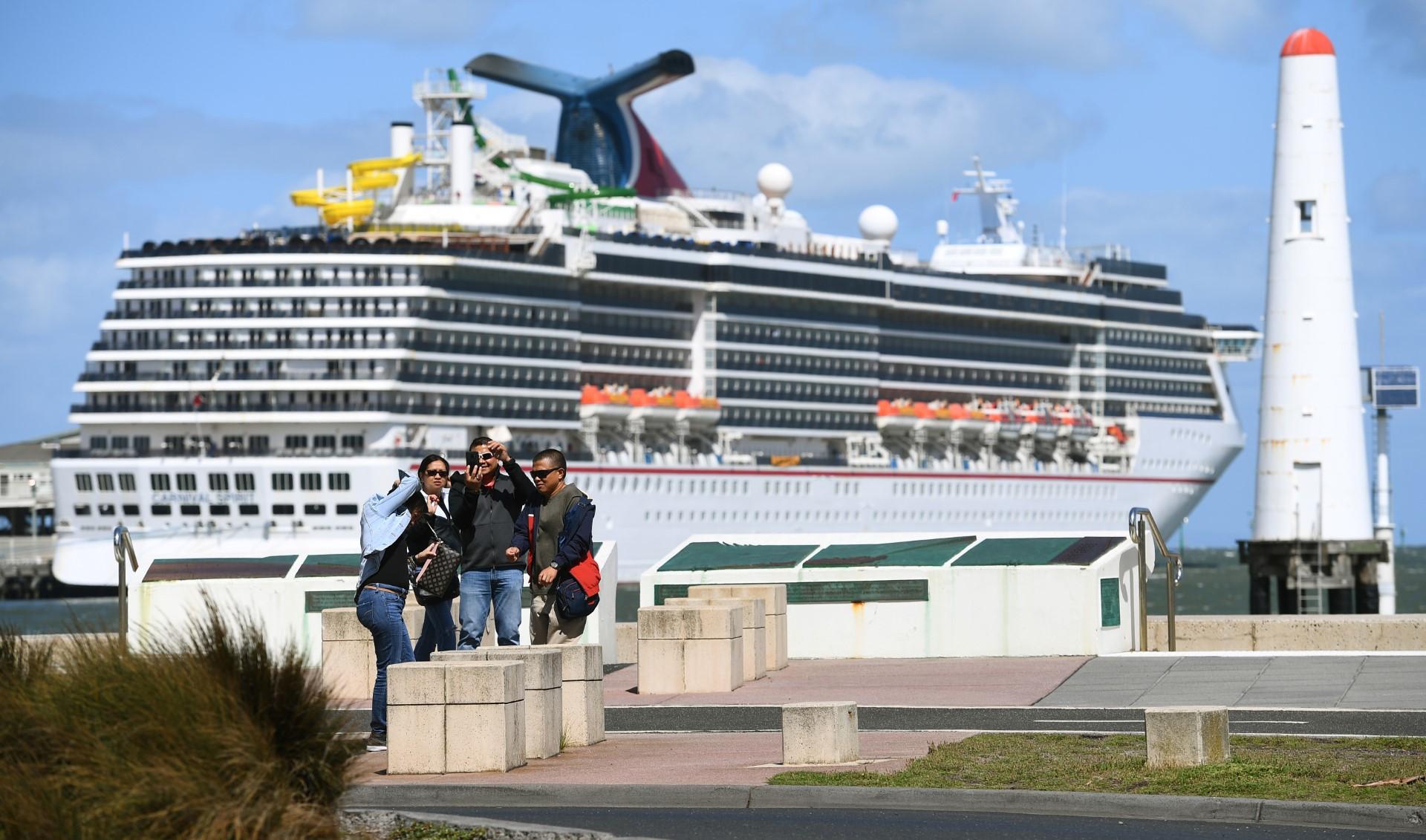 A photo taken in Melbourne on March 14, 2020 shows tourists taking photos in front of a cruise liner docked at Station Pier as Australian Prime Minister Scott Morrison on March 15 announces all cruise ships will be banned entirely from docking in Australia. Photo: AFP
