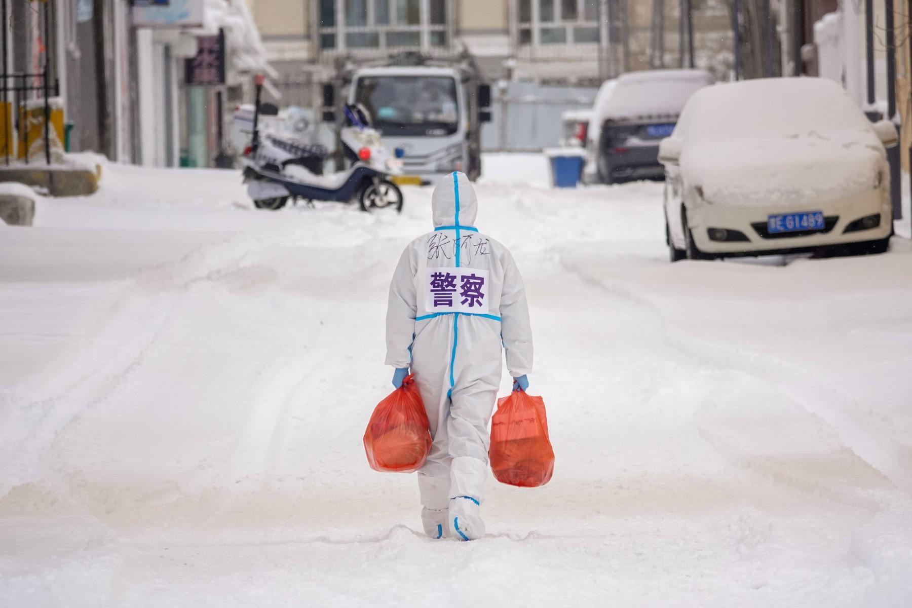 A police officer wearing personal protective equipment carries food and daily supplies that will be distributed to residents at a restricted residental area due to the spread of the Covid-19 coronavirus in Manzhouli in China's northern Inner Mongolia region on March 15. Photo: AFP