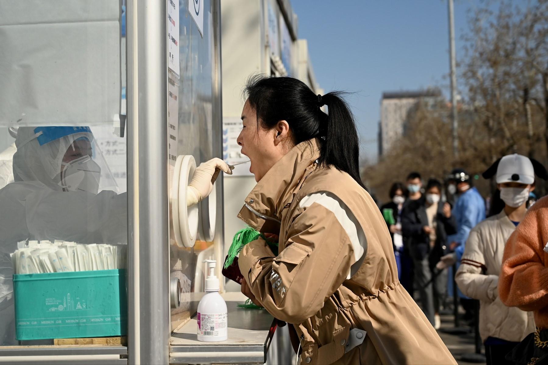 A health worker takes a swab sample on a woman to be tested for the Covid-19 coronavirus in Beijing on March 14, amid a record surge of infections across China.  Photo: AFP
