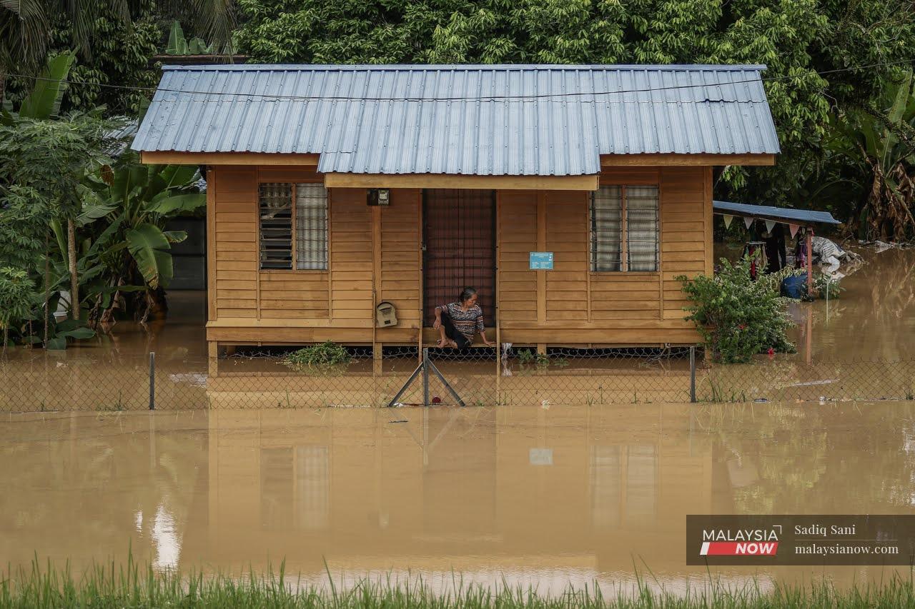 A woman sits at the porch of her house in Bukit Dukong, Hulu Langat, which was left cut off by the rising floods last December.