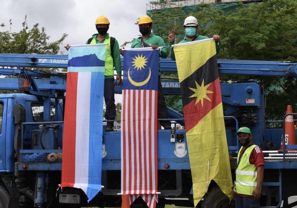 Kakitangan Majlis Perbandaran Kota Kinabalu mengangkat Jalur Gemilang bersama bendera Sabah dan Sarawak pada Hari Malaysia tahun lalu. Gambar: Bernama