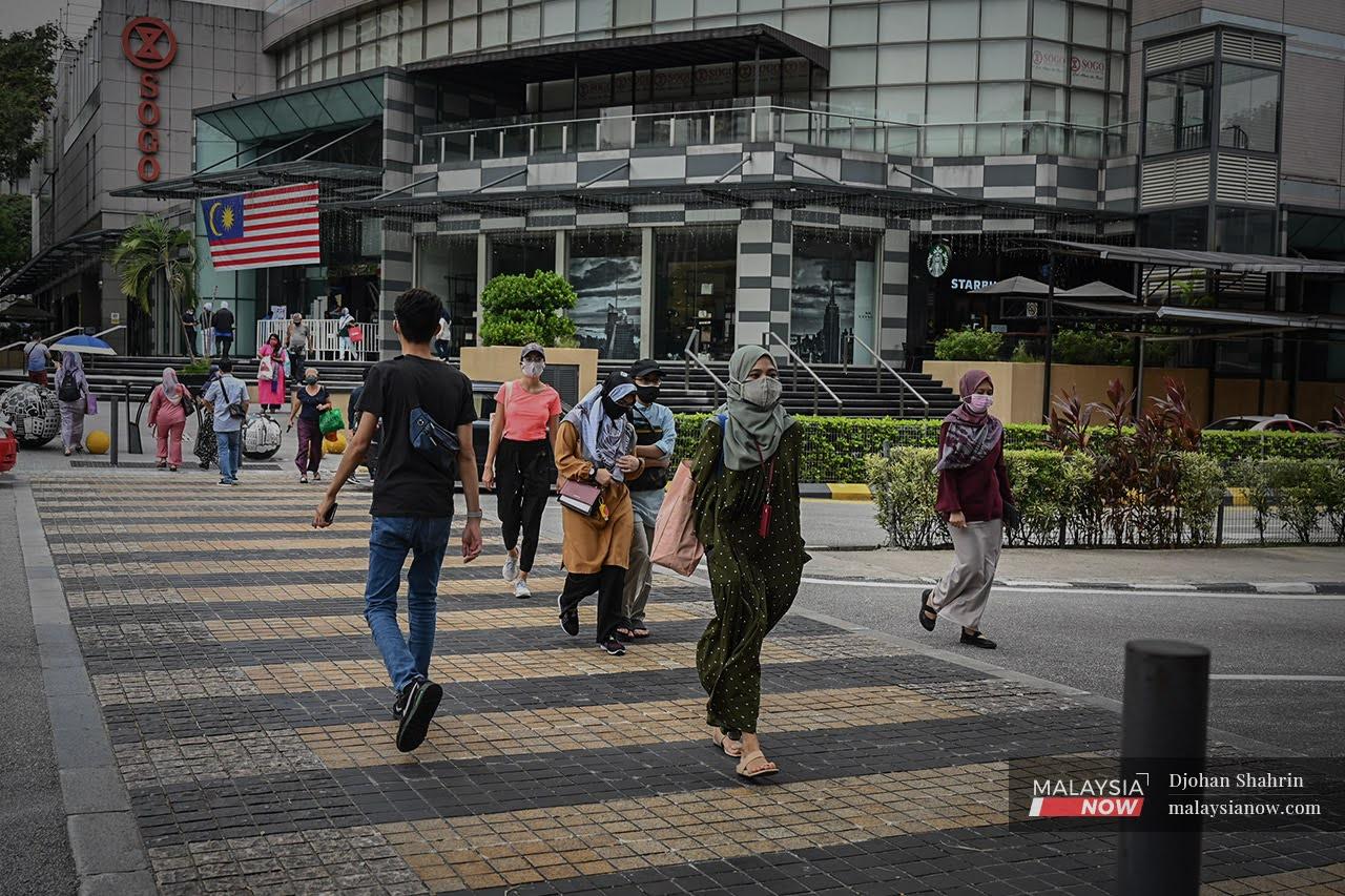 Pedestrians wearing face masks to curb the spread of Covid-19 cross the road at Jalan Tuanku Abdul Rahman in Kuala Lumpur.