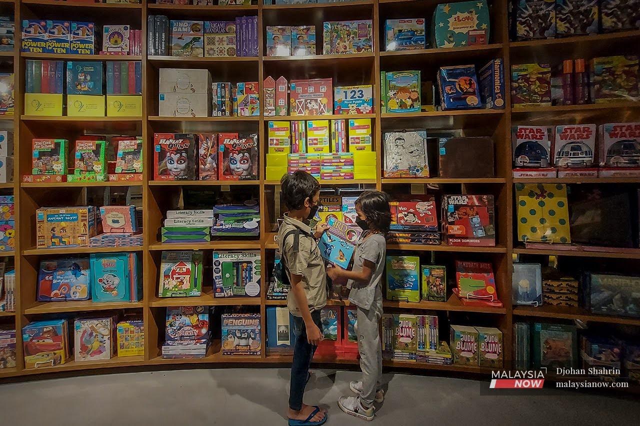 Dua kanak-kanak mencari buku aktiviti di sebuah kedai buku di Sun Suria, Setia Alam.