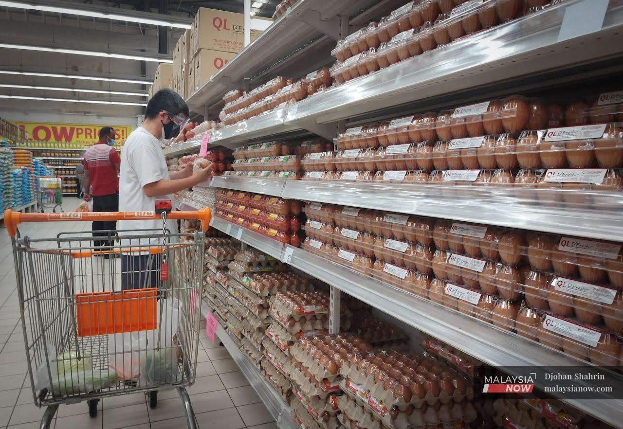 Seorang lelaki memeriksa telur yang ingin dibelinya di sebuah pasar raya di ibu negara Kuala Lumpur.