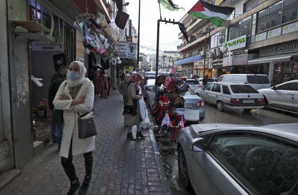 Warga Palestin berjalan di hadapan deretan kedai Tebing Barat, Ramallah pada Disember 2021. Gambar: AFP