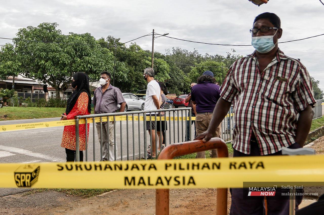 Pengundi Durian Tunggal pada PRN Melaka beratur menunggu giliran membuang undi dengan memakai pelitup muka bagi mencegah jangkitan Covid-19.