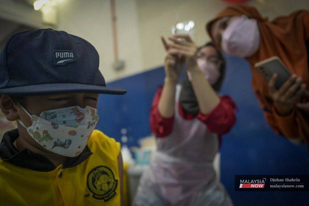 A child winces as he waits to receive a dose of Covid-19 vaccine for children at the Dewan Komuniti Taman Bukit Mewah vaccination centre in Kajang.