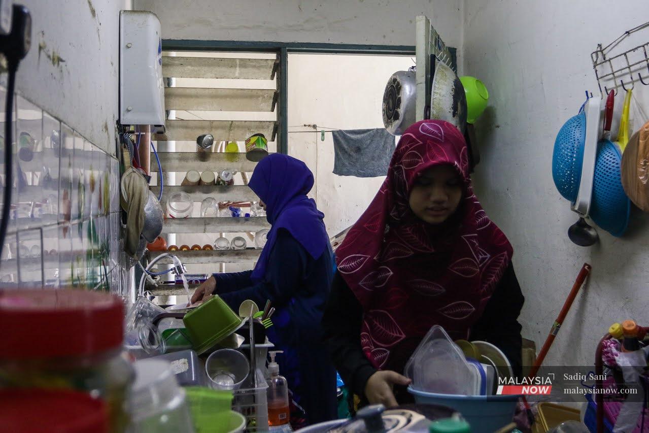 Kak Nani and her daughter work together in the tiny kitchen of their home at a low-cost housing unit in Petaling Jaya.