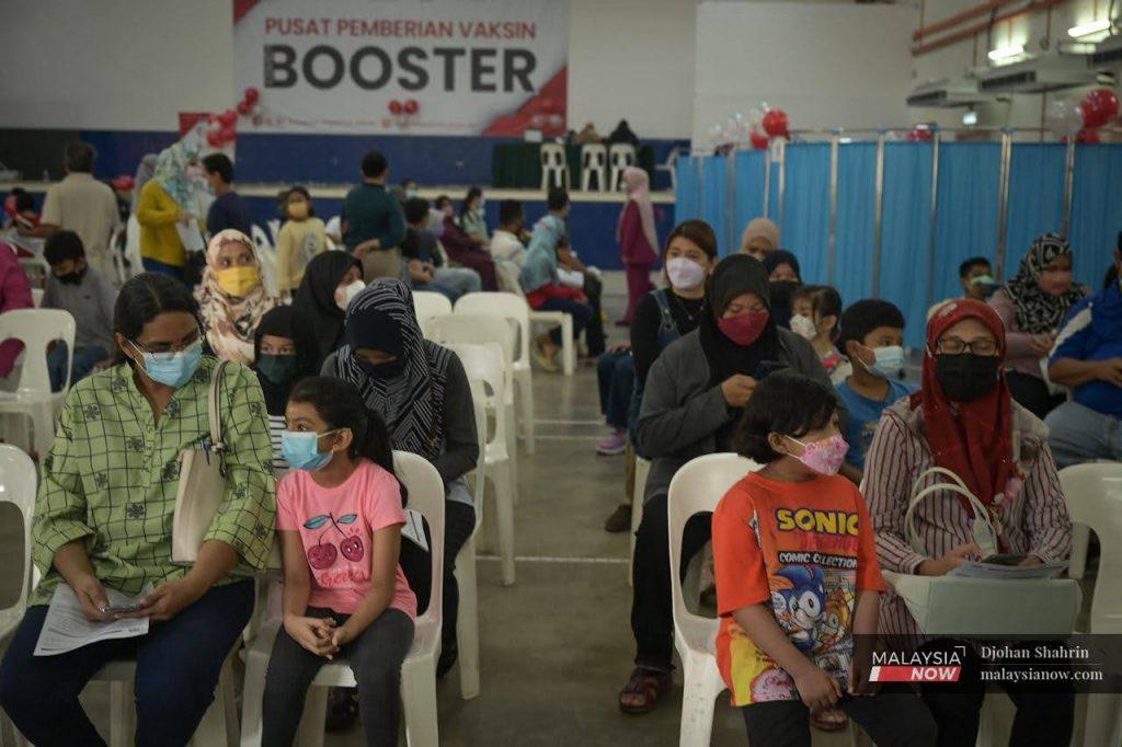Children wait with their parents and guardians to receive a dose of Covid-19 vaccine at the Dewan Komuniti Taman Bukit Mewah vaccination centre in Kajang.