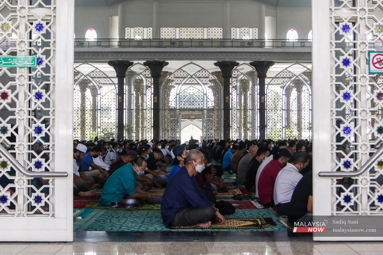 Congregants sit on prayer mats before performing the Friday prayers at the Sultan Abdul Samad Mosque in KLIA, Sepang, after social distancing restrictions are eased as the country transitions towards the endemic phase of Covid-19.