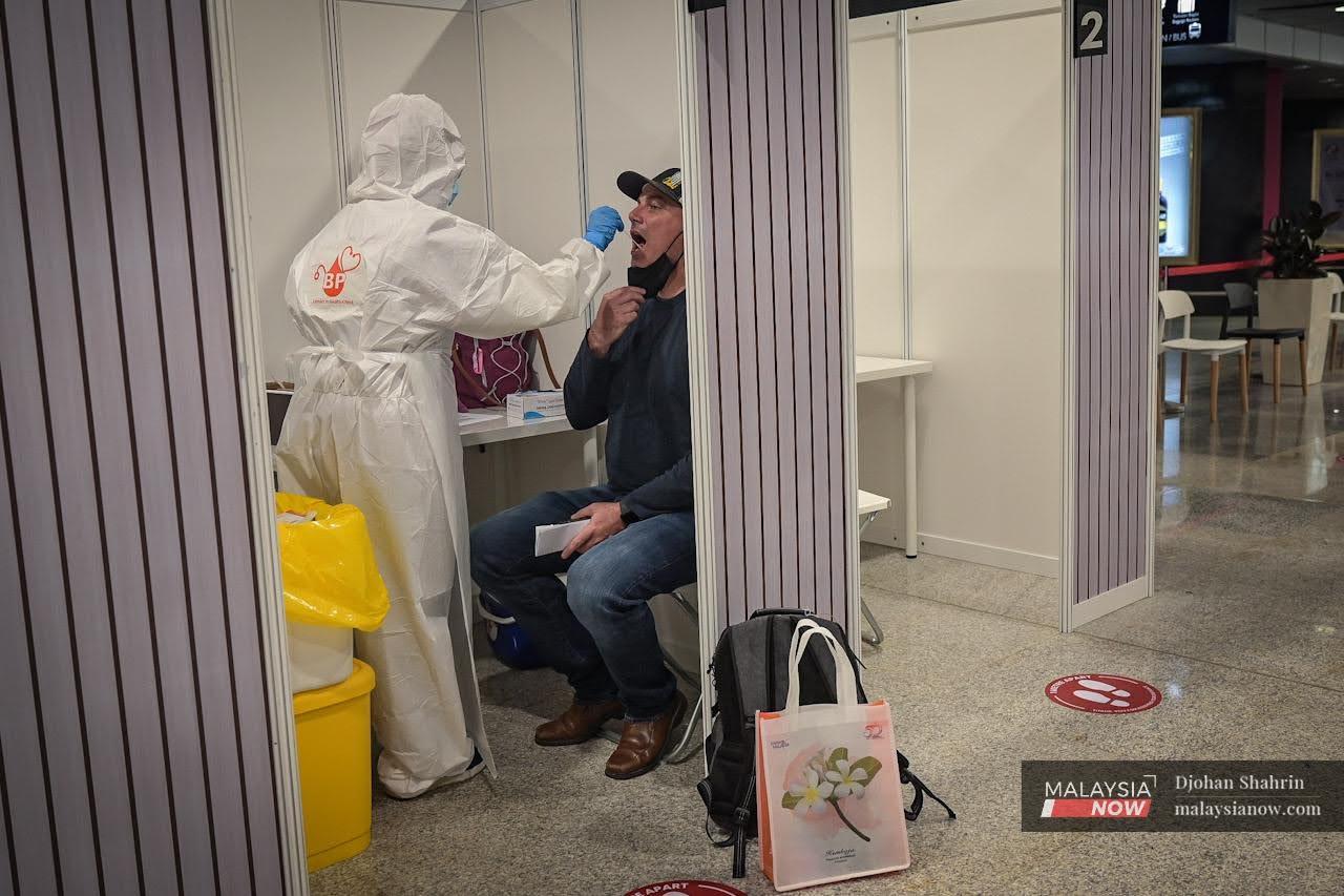 A traveller from Abu Dhabi undergoes a swab test for Covid-19 at the arrival hall in KLIA, Sepang.