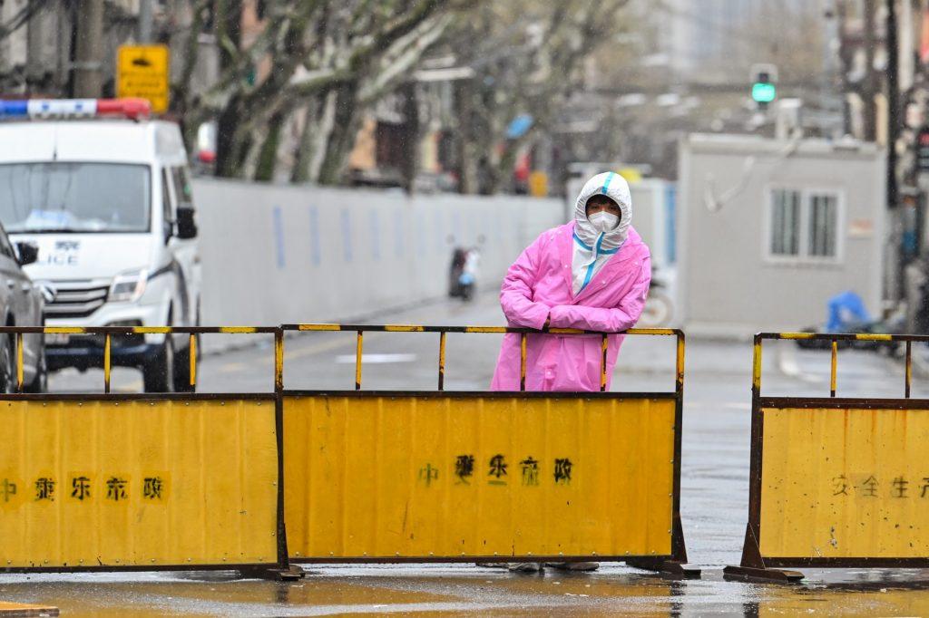 A worker wearing protective gear stands next to barriers placed to close off streets around a locked down neighbourhood after the detection of new cases of Covid-19 in the Huangpu district of Shanghai on March 21. Photo: AFP