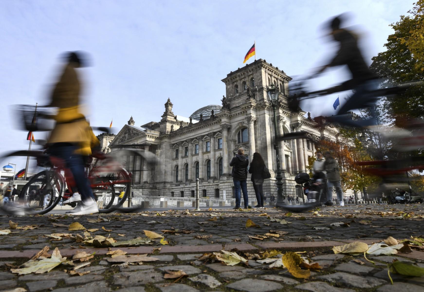 Leaves lay on the ground as pedestrians and bicycle riders are seen in front of the Reichstag building housing the lower house of parliament Bundestag in Berlin, Germany, on Oct 19, 2021. Photo: AFP