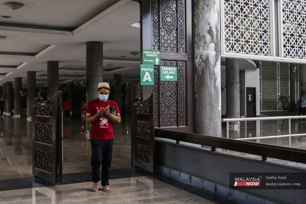 Seorang lelaki memakai pelitup muka bagi mengelak jangkitan Covid-19 ketika memasuki ruang solat di Masjid Sultan Abdul Samad.
