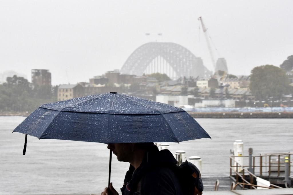 A man walks in front of the Harbour Bridge during rainfall in Sydney on April 7, as inclement weather triggered evacuation orders in several suburbs of Sydney's south and southwest. Photo: AFP
