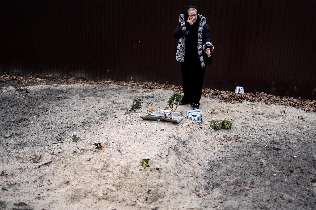 A woman weeps over the grave of her son, buried in the garden of her house in Bucha, northwest of Kyiv, on April 6. Photo: AFP