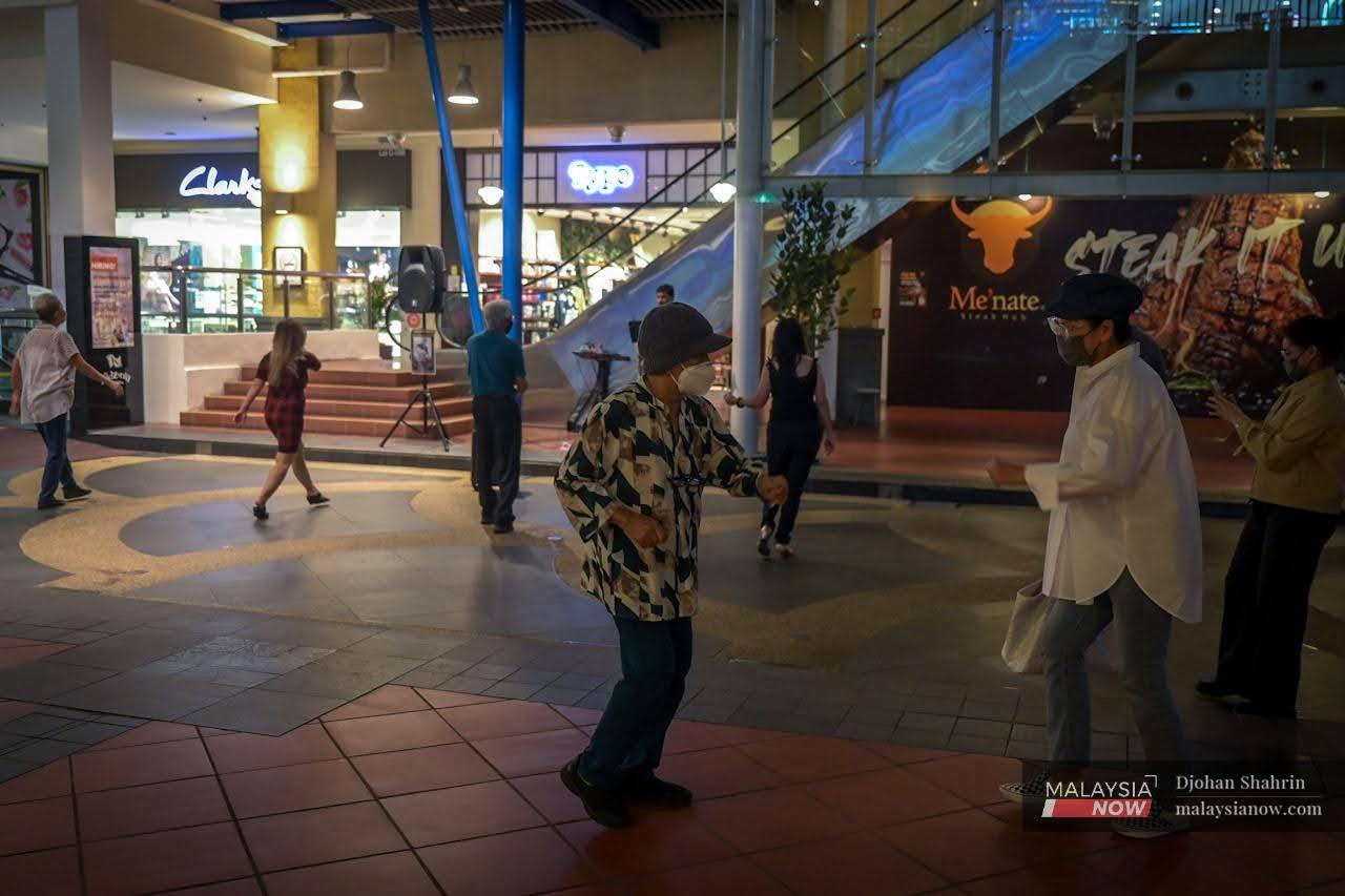 Beberapa pengunjung kompleks membeli belah The Curve menari sambil memakai pelitup muka semasa persembahan seorang busker di hadapan kedai kopi Starbucks di Mutiara Damansara.