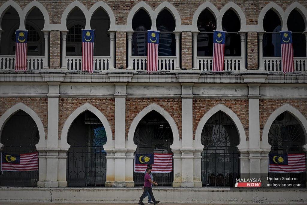 Pedestrians walk past the Sultan Abdul Samad building in Kuala Lumpur. Making Bahasa Melayu the second language in the region will enhance Malaysia's image in the eyes of the world but might affect economic growth, an economist says.