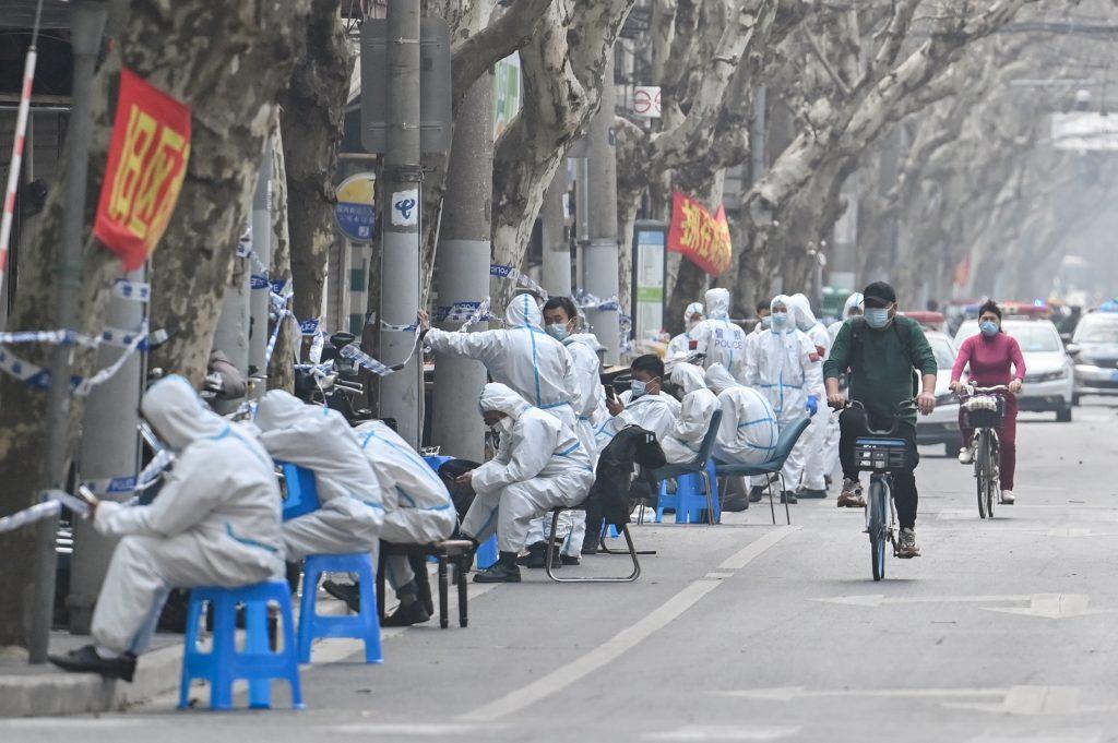 Workers are seen wearing protective clothes next to some lockdown areas after the detection of new cases of covid-19 in Shanghai on March 14. Photo: AFP