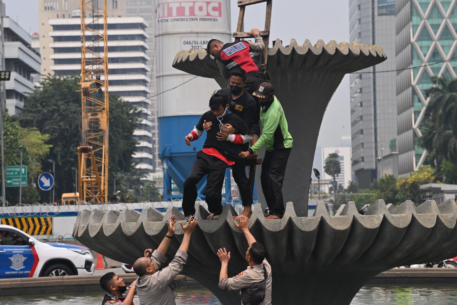 Police arrest a protester who climbed a fountain near the presidential palace during a protest by students against high prices of supplies, the postponement of presidential elections and an extension of the president's term, in Jakarta on April 11. Photo: AFP