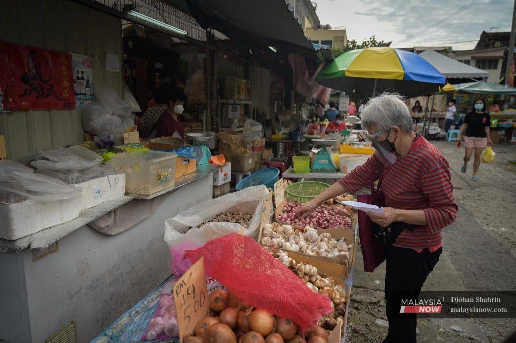 A woman stops to buy garlic at a sundry shop at the Ampang market in Selangor.