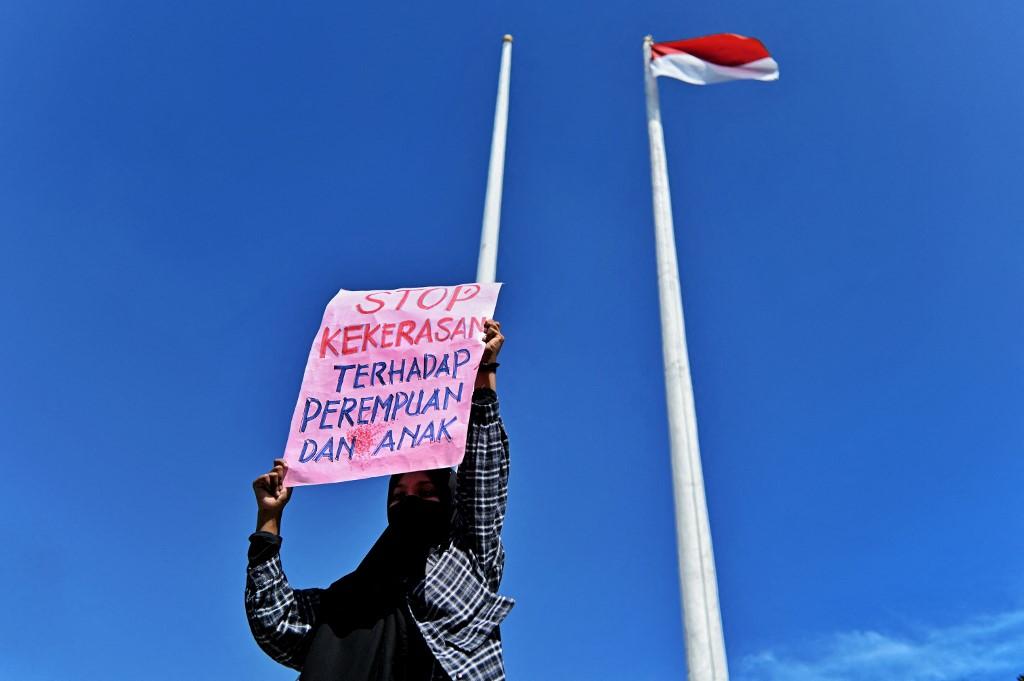 Serorang wanita memegang plakad protes keganasan seksual di Aceh pada Disember 2021. Gambar: AFP