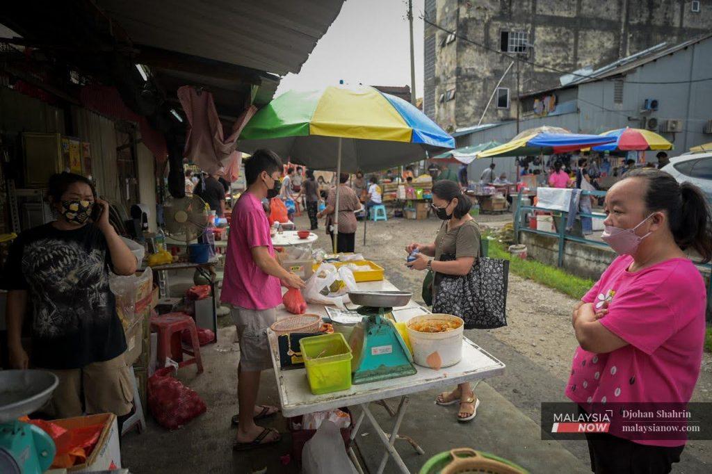 A customer pays for her purchases at a sundry shop at the Ampang market in Selangor.