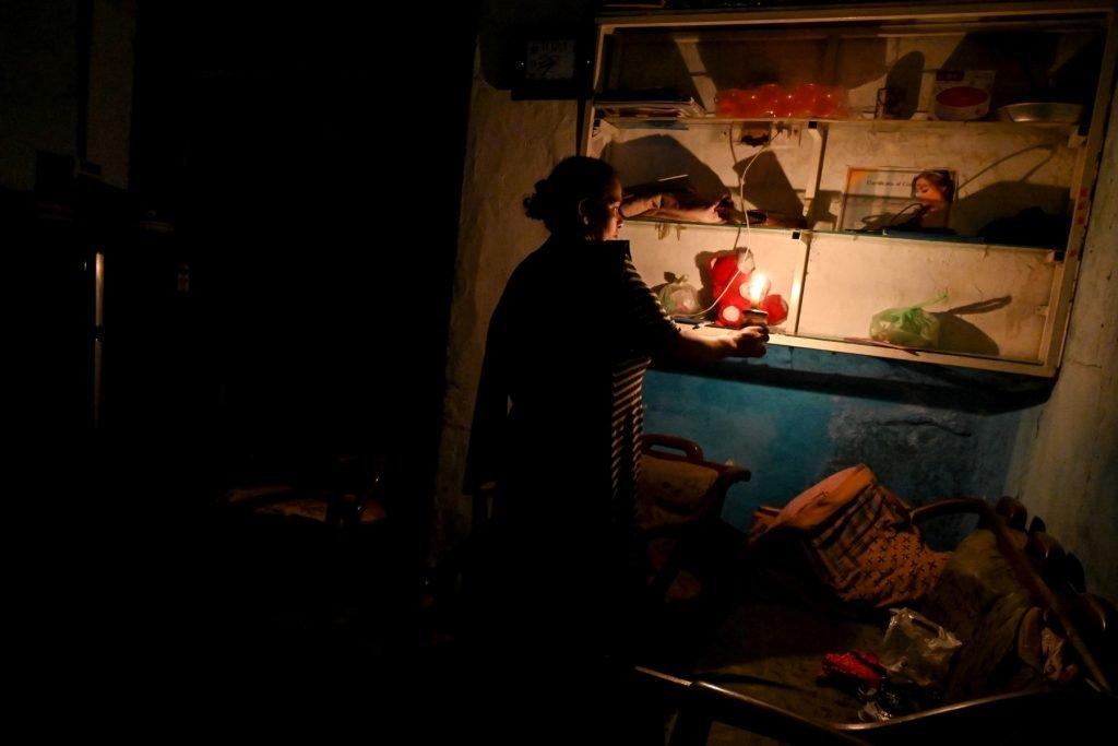 A woman uses a candle inside her house during a power cut in Colombo on March 30. Photo: AFP