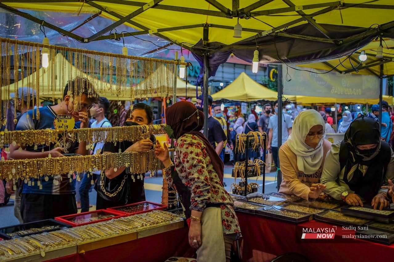 A trader selling jewellery haggles with a customer at the Ramadan bazaar in Jalan Tunku Abdul Rahman, Kuala Lumpur, ahead of Hari Raya which will be celebrated in early May.