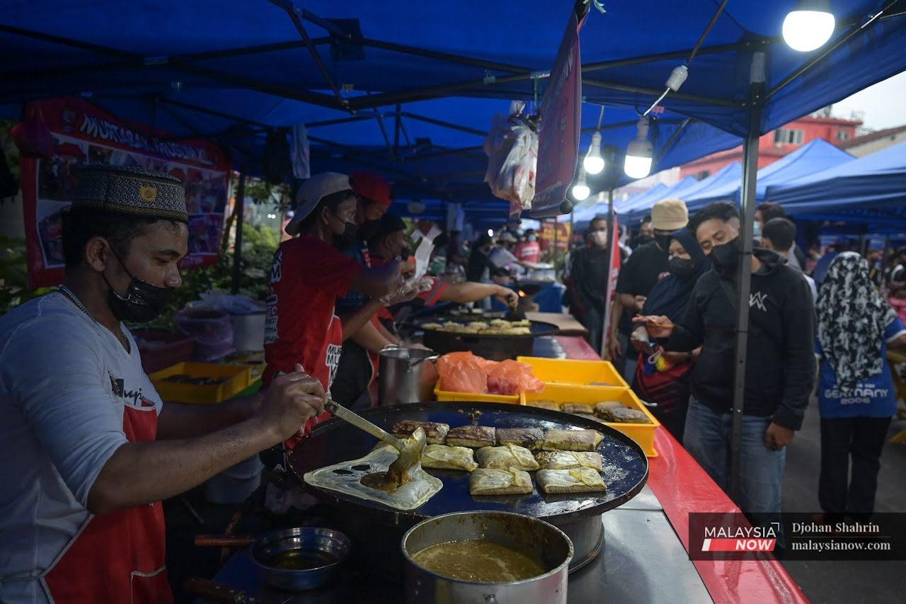Pelanggan memakai pelitup muka ketika beratur menunggu pesanan murtabak di pasar Ramadan Jalan Raja Alang, Kampung Baru.