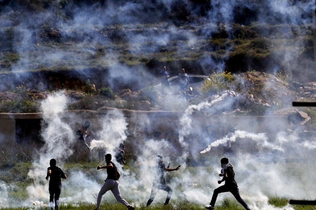 Palestinians run for cover from tear gas during clashes with Israeli security forces at the northern entrance of Ramallah, near the Israeli settlement of Beit El, in the occupied West Bank, on April 11. Photo: AFP