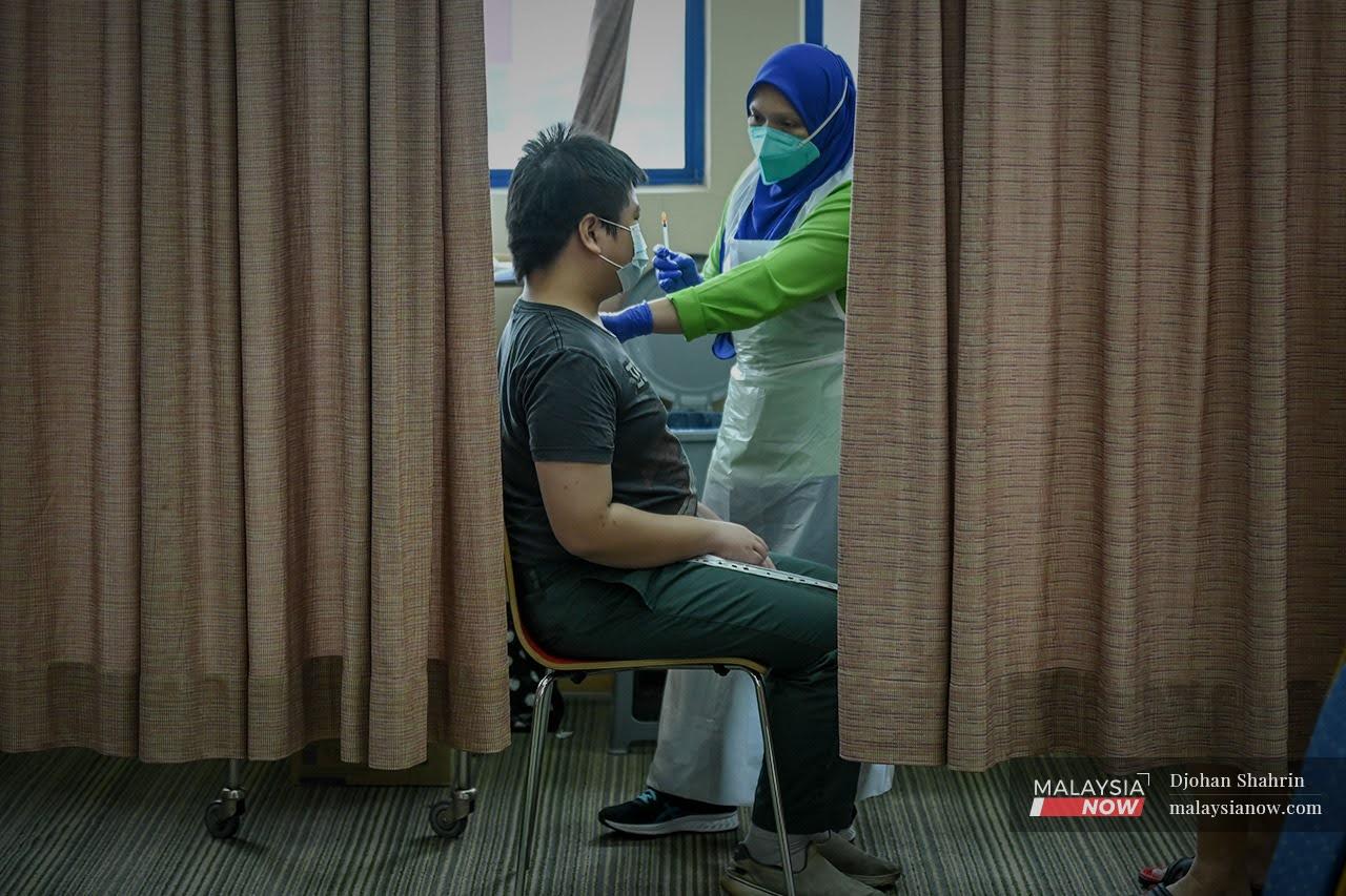 Petugas kesihatan menunjukkan picagari kosong selepas memberikan suntikan vaksin Pfizer Bio-NTech kepada seorang remaja di PPV KPJ Tawakkal, Jalan Pahang.