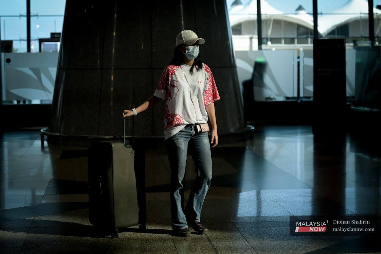 A traveller wearing a face mask pulls a luggage bag behind her at KLIA in Sepang. The government recently announced that non-medical face masks would require approval from Sirim, sparking debate over whether such a move is needed.