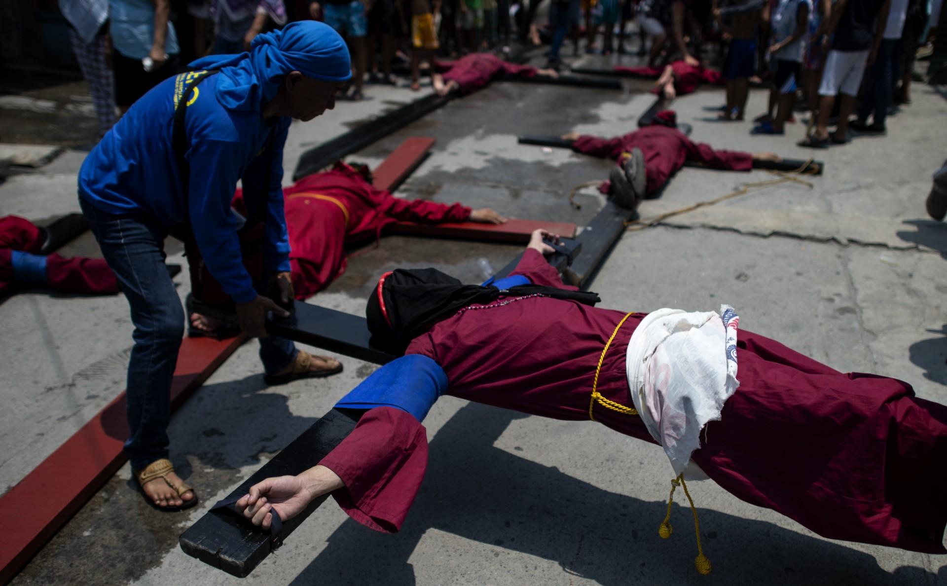 Men lie on crosses on a street in Mabalacat, Pampanga on April 18, 2019, one day ahead of the reenactment of the crucifixion of Jesus Christ on Good Friday. Photo: AFP