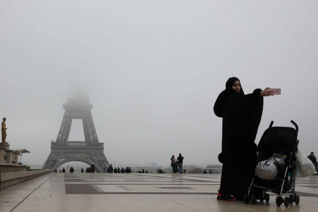 A tourist takes a selfie on the Trocadero plaza, in front of the Eiffel tower hidden by a heavy fog on Nov 15, 2018, in Paris. Photo: AFP