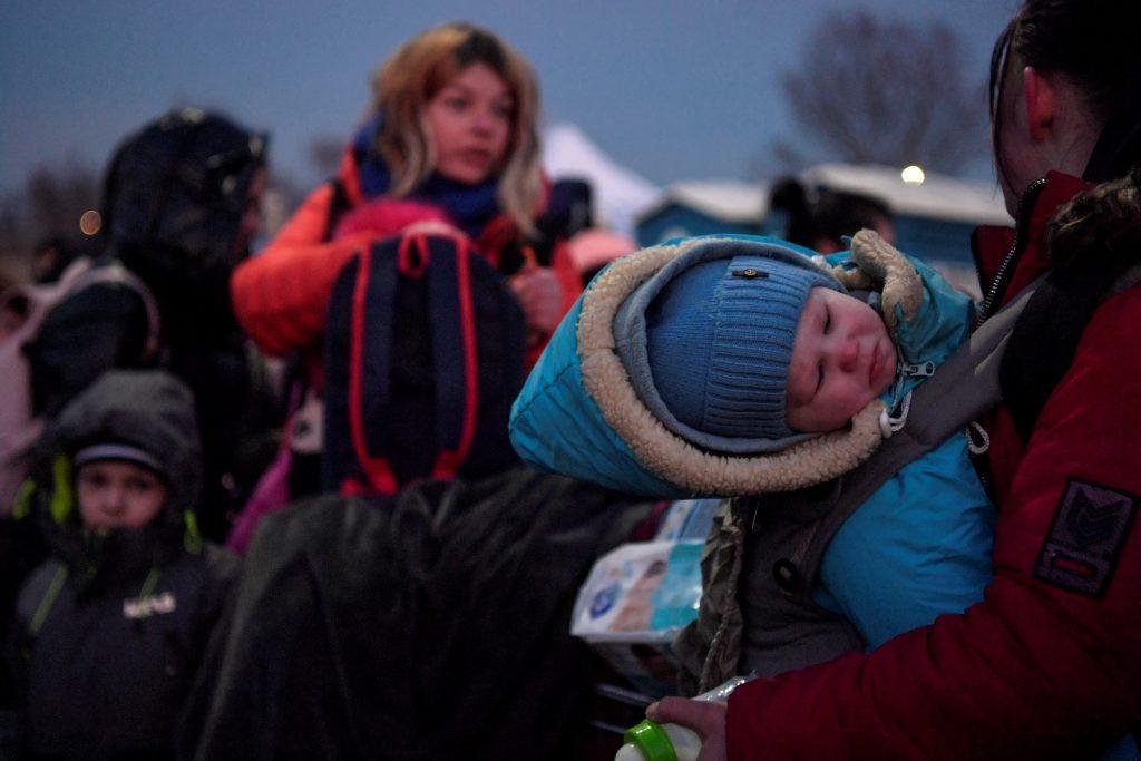 A child is carried by a woman as refugees from Ukraine proceed to a gathering point after crossing the Ukrainian border with Poland at the Medyka border crossing, southeastern Poland, on March 11. Photo: AFP