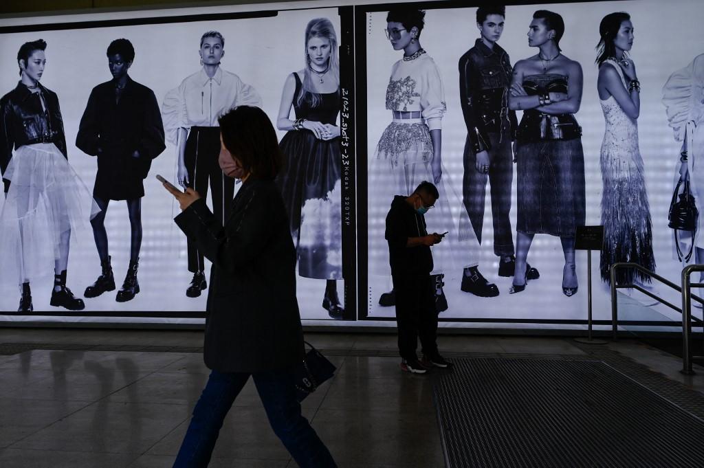 People walk past an advertisement in Beijing on April 14. With infections found in dozens of cities, Beijing has dug in its heels on the zero-Covid approach. Photo: AFP
