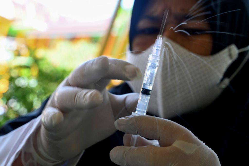 A health worker prepares a syringe with the Sinovac vaccine against Covid-19 at an elementary school in Banda Aceh on Feb 9. Indonesia's daily case numbers have decreased significantly since a spike in February driven by the Omicron variant. Photo: AFP