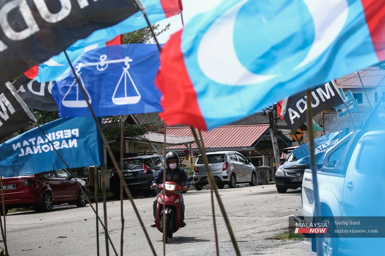 A motorcyclist makes his way past the flags of various parties set up at a junction near Kampung Melayu Majidee ahead of the Johor state election on March 12.