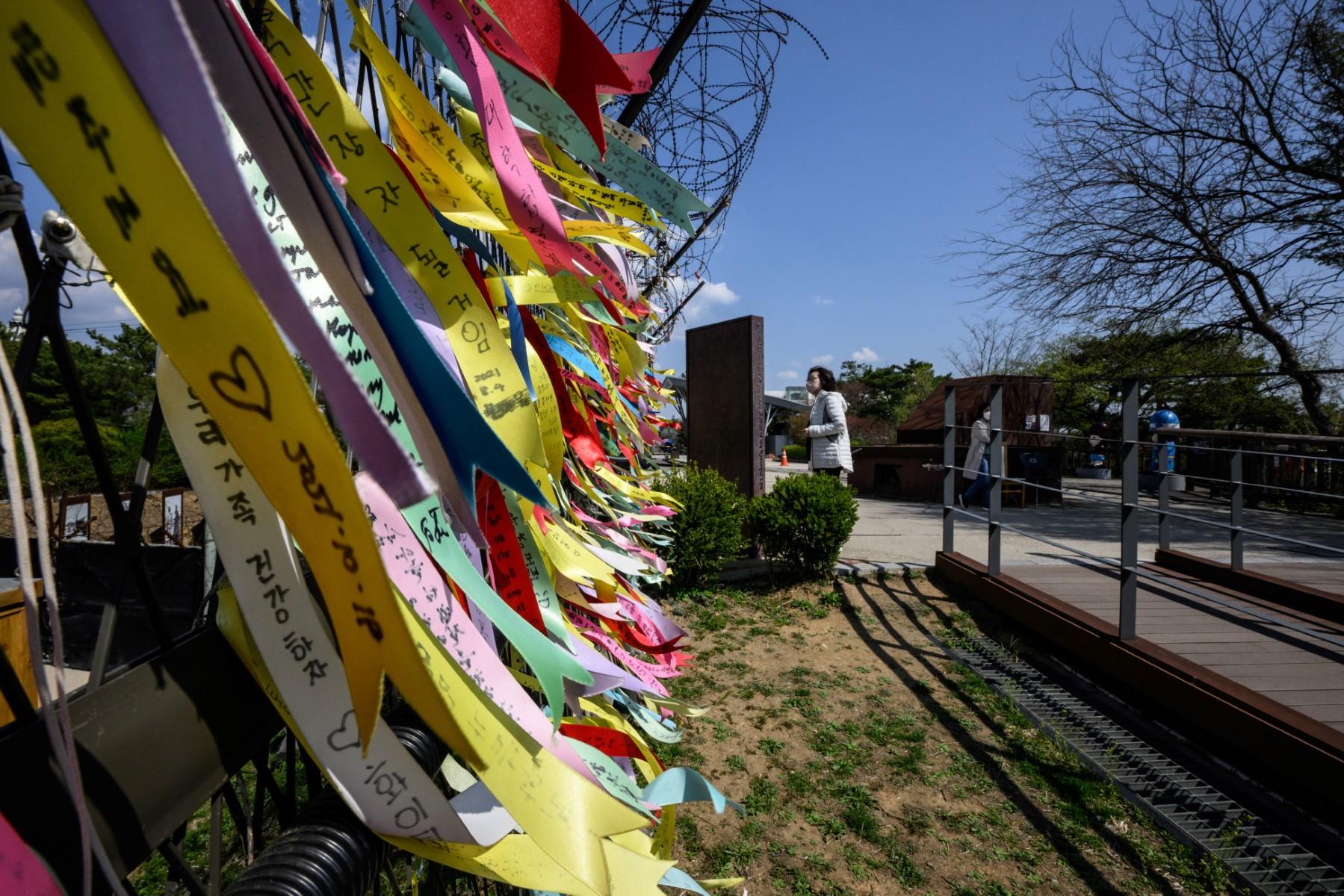 A visitor looks at an information board near a fence adorned with ribbons with messages written on them, at the Imjingak 'peace park' near the Demilitarized Zone separating North and South Korea, in Paju on April 15. Photo: AFP