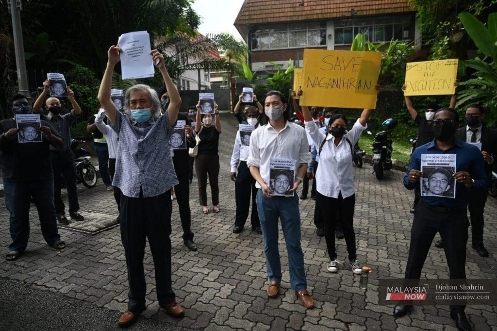Activists hold up posters showing the face of Nagaenthran K Dharmalingam, a Malaysian facing execution in Singapore for a conviction of drug trafficking, in a protest outside the Parliament building last November.