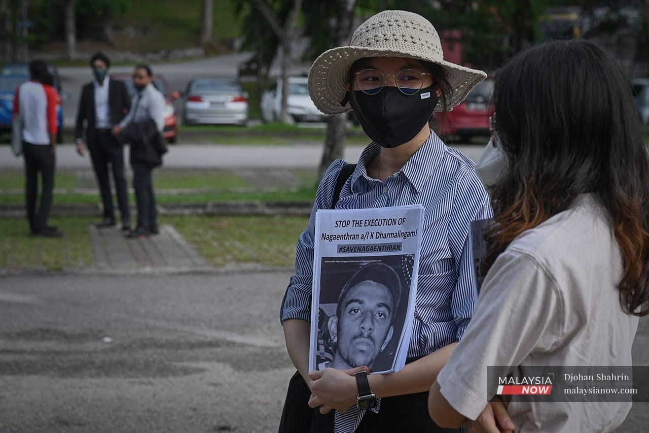 An activist holds a stack of pamphlets featuring Nagaenthran K Dharmalingam's picture during a protest outside Parliament in Kuala Lumpur last November.