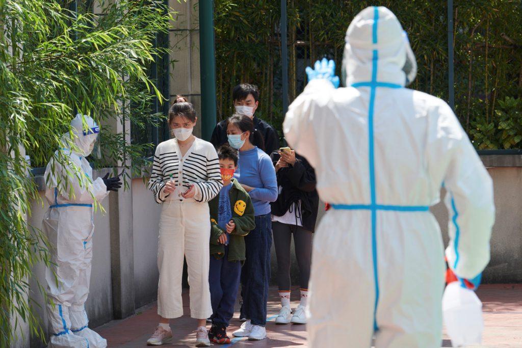 Community volunteers wearing personal protective equipment guide residents queuing to get tested for Covid-19 in a compound during a lockdown in Pudong district in Shanghai on April 17. Photo: AFP
