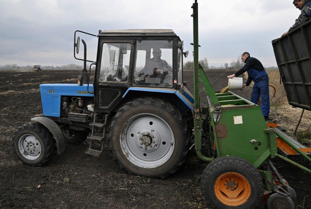 Farmers load oat in the seeding-machine to sow in a field east of Kyiv on April 16. Photo: AFP