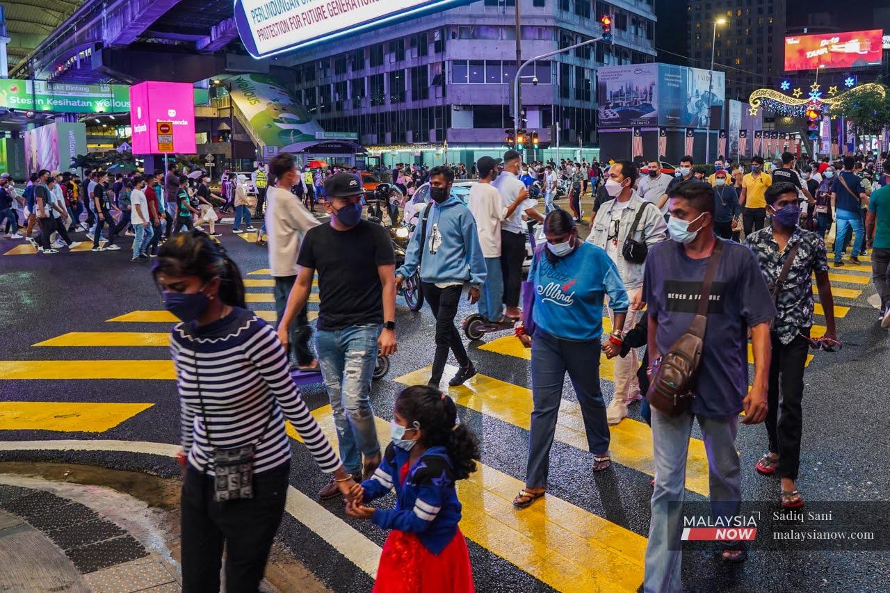 Pedestrians wearing face masks to curb the spread of Covid-19 cross a junction in the Bukit Bintang shopping district in Kuala Lumpur.