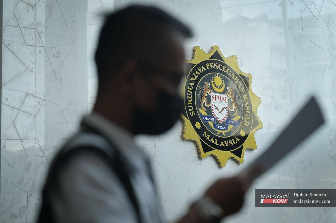 A man walks past the logo of the The Malaysian Anti-Corruption Commission at the agency's headquarters in Putrajaya. The commission says it is responsible for verifying and investigating any report or official complaint involving issues within its purview.